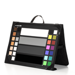 Load image into Gallery viewer, Calibrite ColorChecker Video XL chart held up on a film set, showing its various color and grayscale patches, with its protective case nearby.