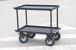 Load image into Gallery viewer, Front three-quarter view of the black Mule Utility Cart, a heavy-duty aluminum production cart with two shelves and large pneumatic wheels.
